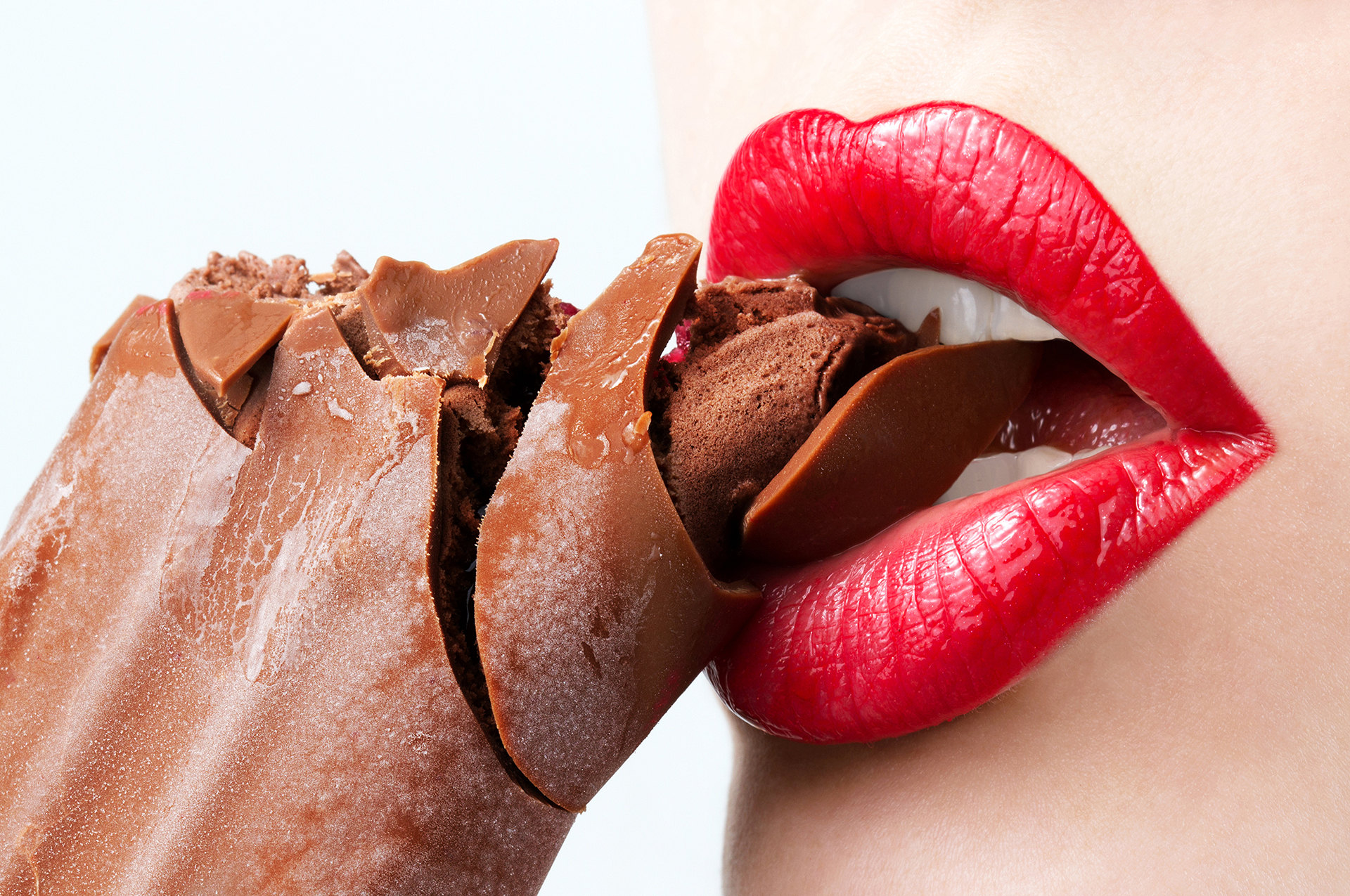 Red lips biting into a piece of chocolate