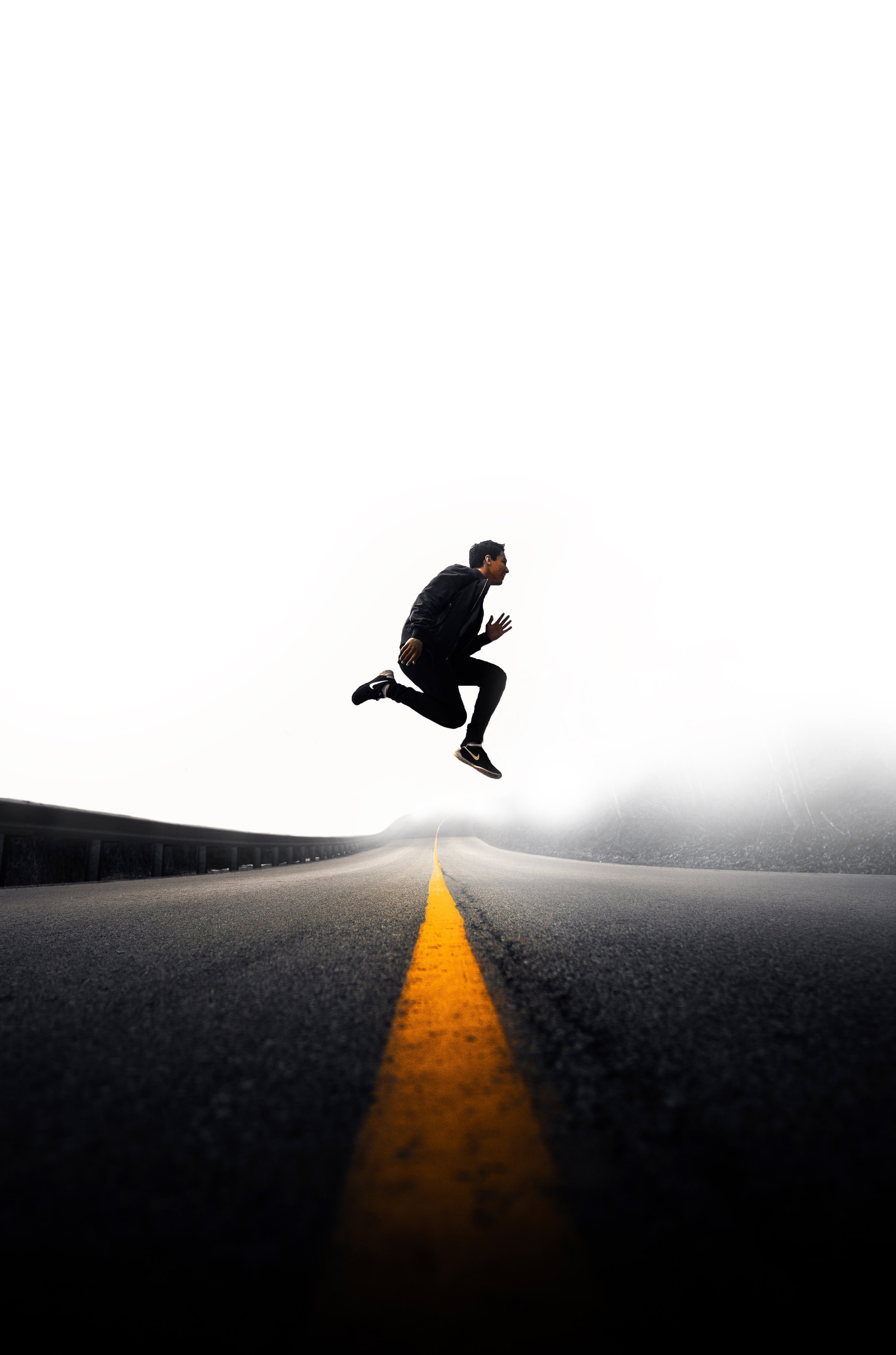 A person leaping over a road marking at dusk