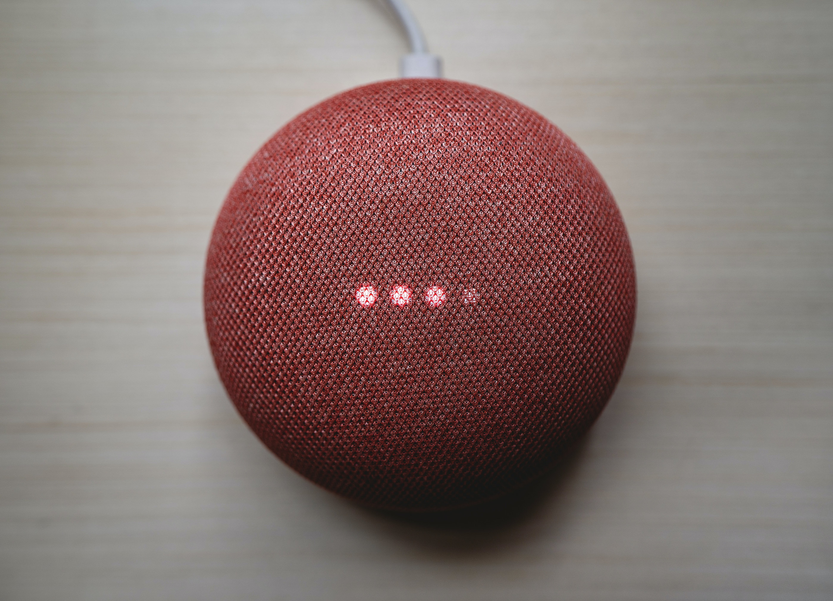 A red fabric-covered smart speaker on a table