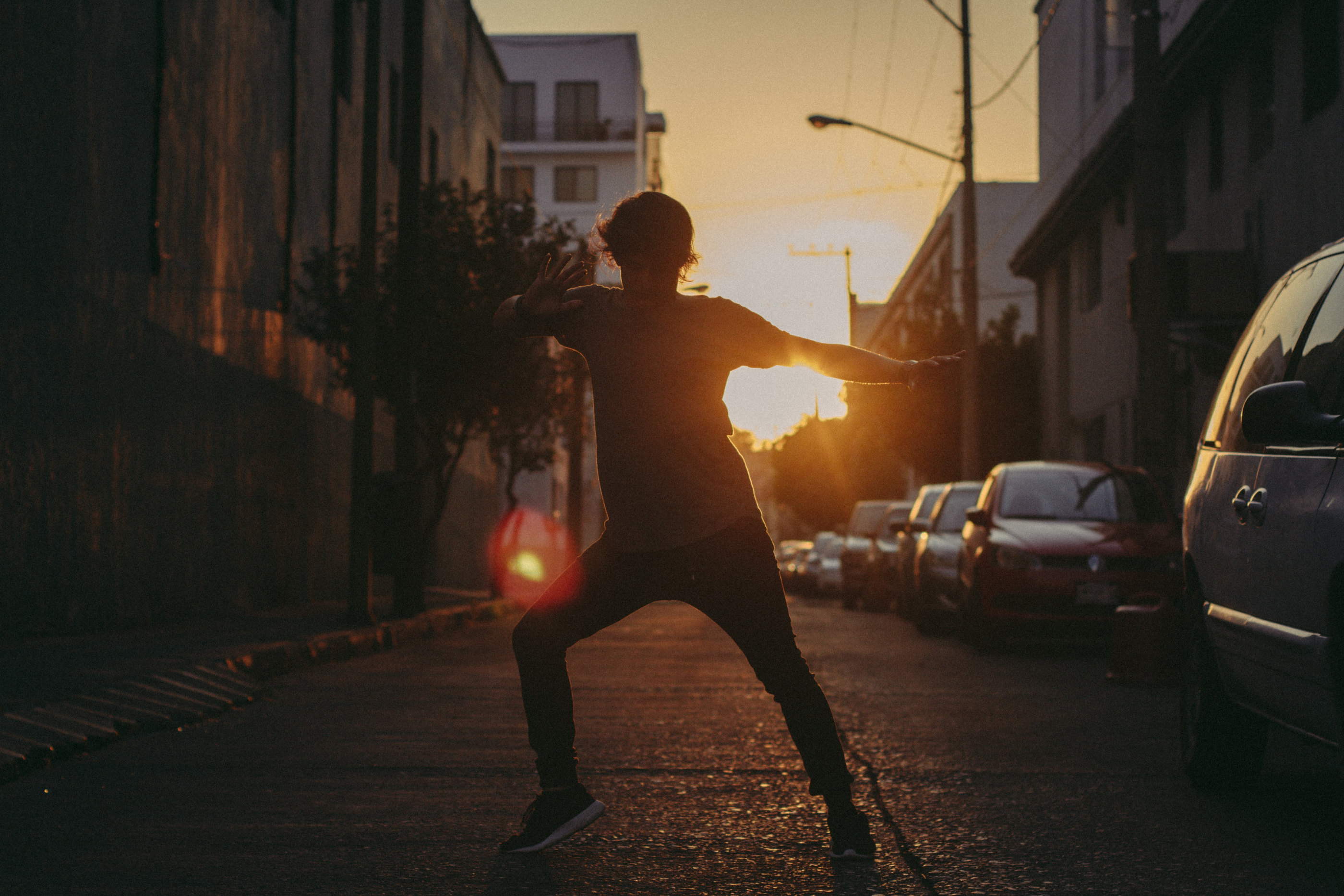 A person standing in a street at sunset holding a light