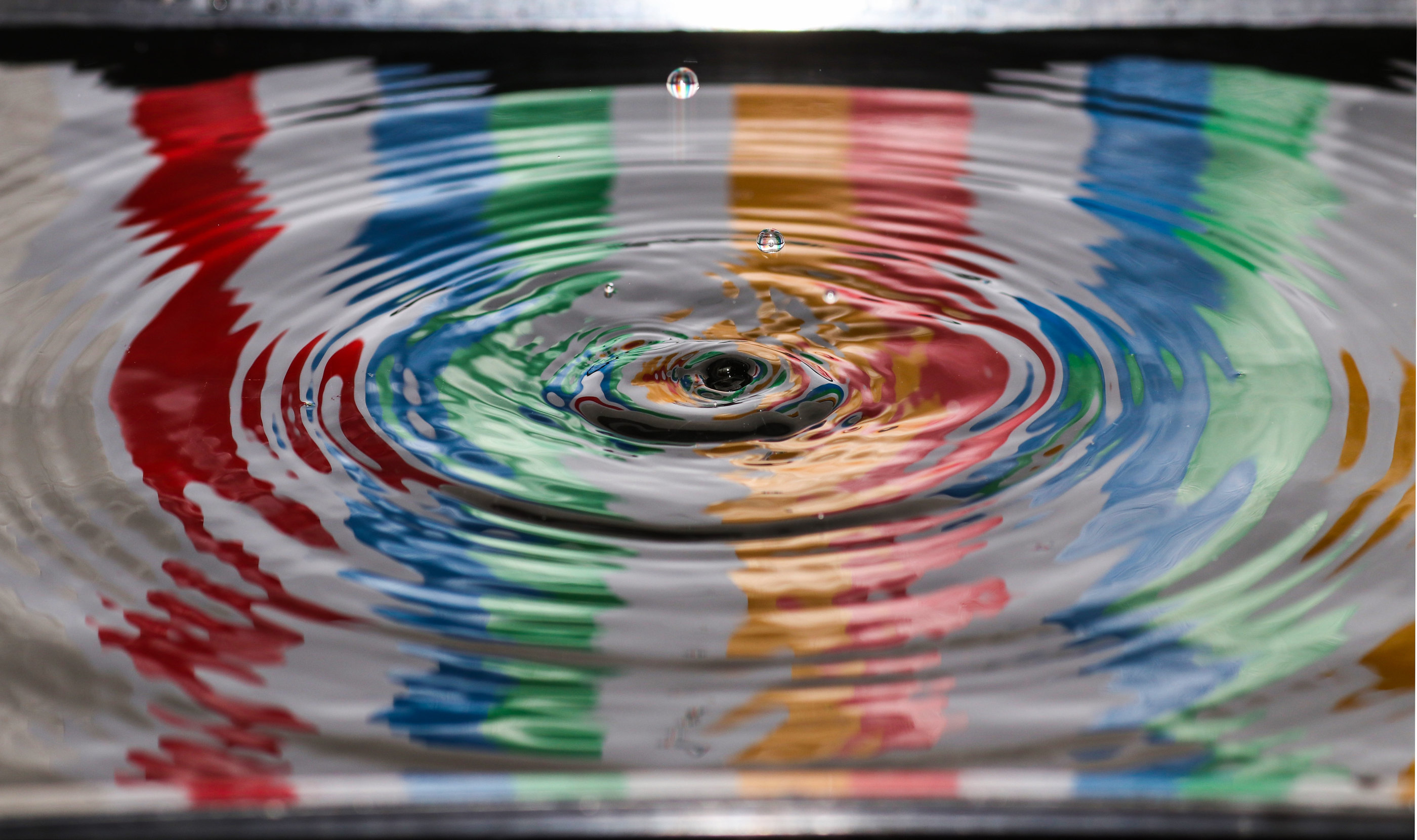 Concentric ripples across colourful reflected water