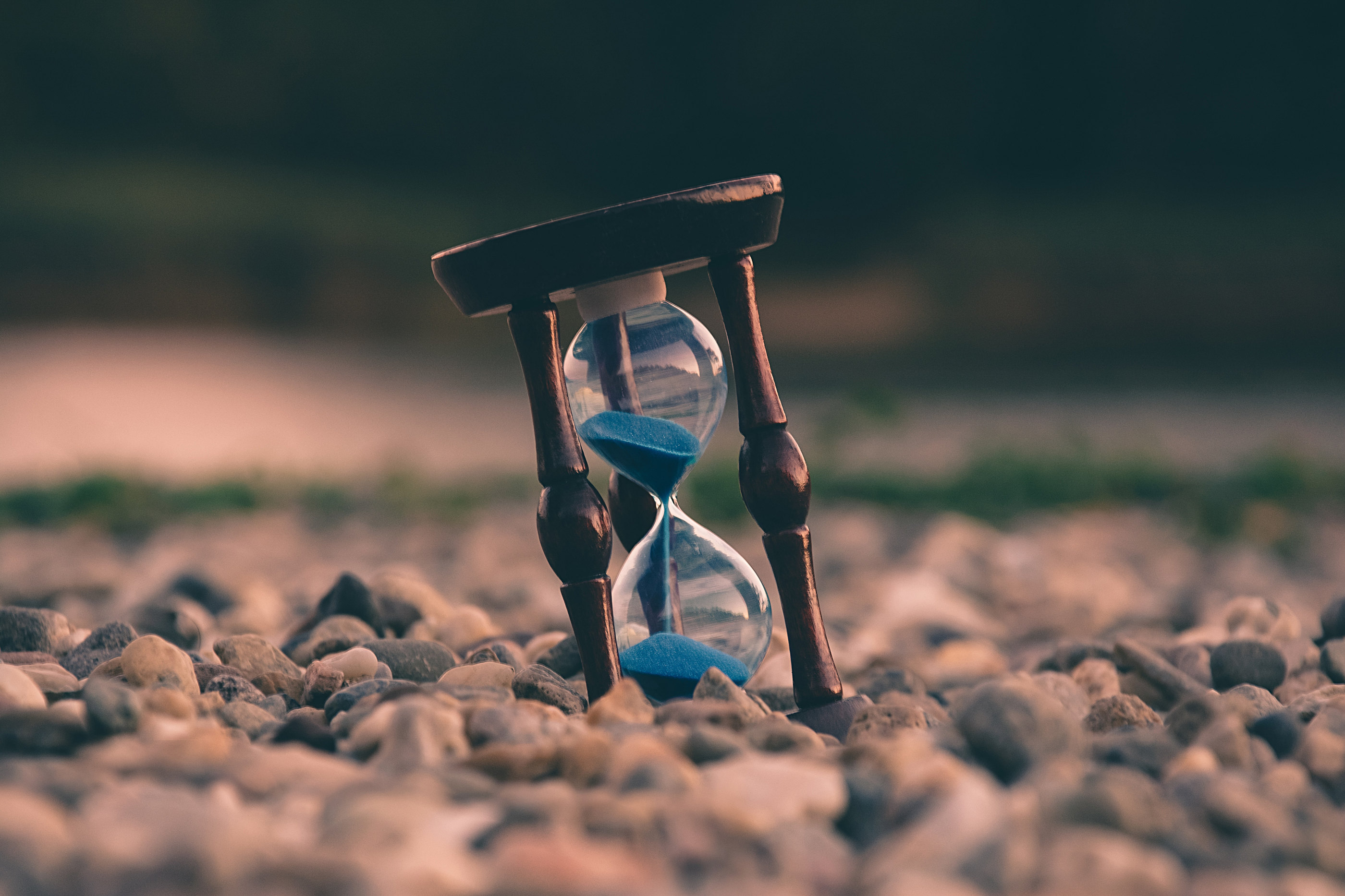 An hourglass standing on stones at sunset